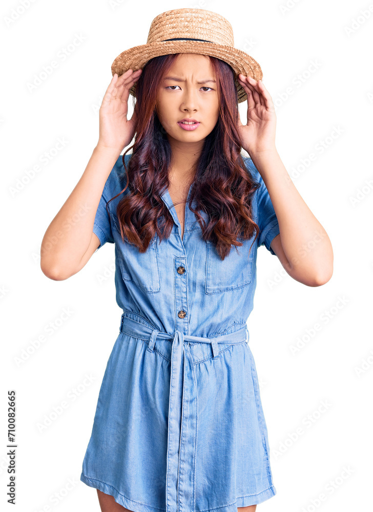Young beautiful chinese girl wearing summer hat trying to hear both hands on ear gesture, curious for gossip. hearing problem, deaf Young beautiful chinese girl wearing summer hat trying to hear both hands on ear gesture, curious for gossip. hearing problem, deaf