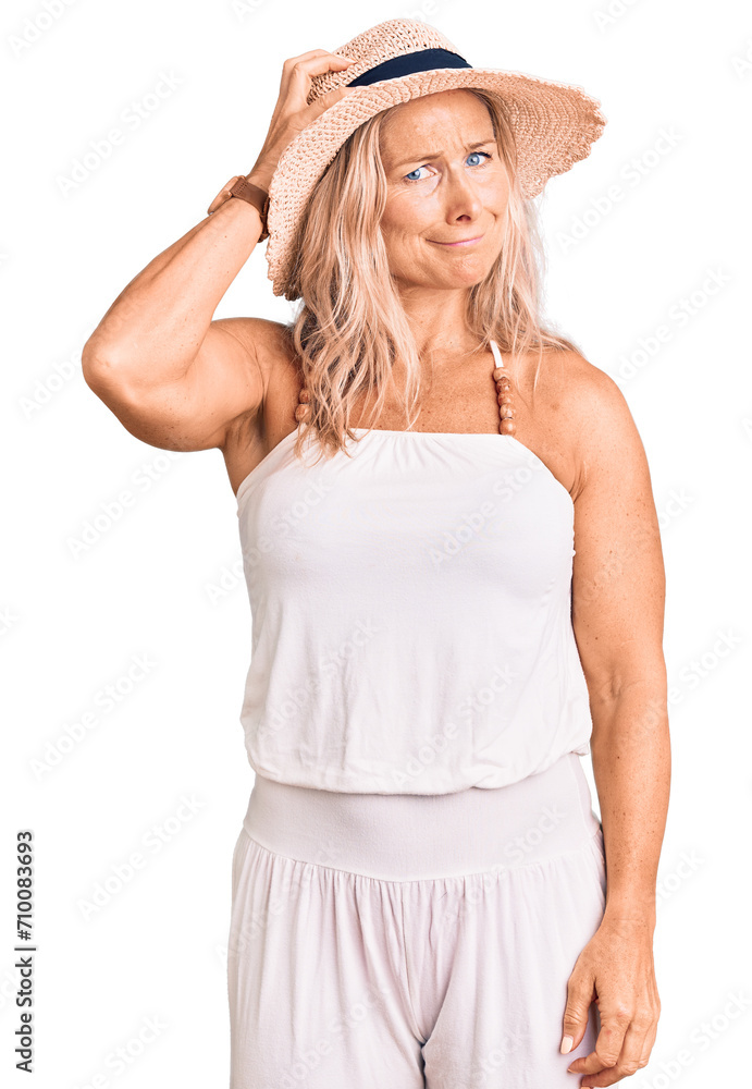 Middle age fit blonde woman wearing summer hat confuse and wonder about question. uncertain with doubt, thinking with hand on head. pensive concept. Middle age fit blonde woman wearing summer hat confuse and wonder about question. uncertain with doubt, thinking with hand on head. pensive concept.