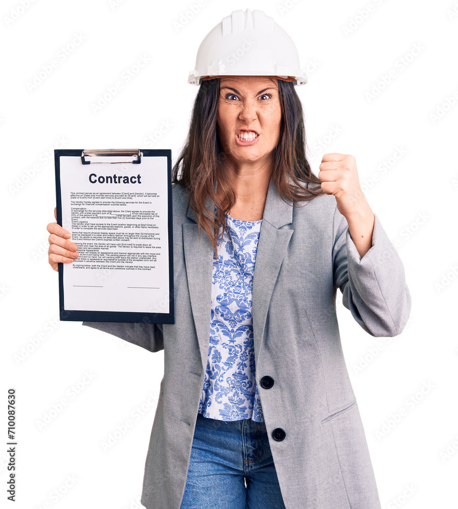 Young beautiful brunette woman wearing architect hardhat holding contract annoyed and frustrated shouting with anger, yelling crazy with anger and hand raised