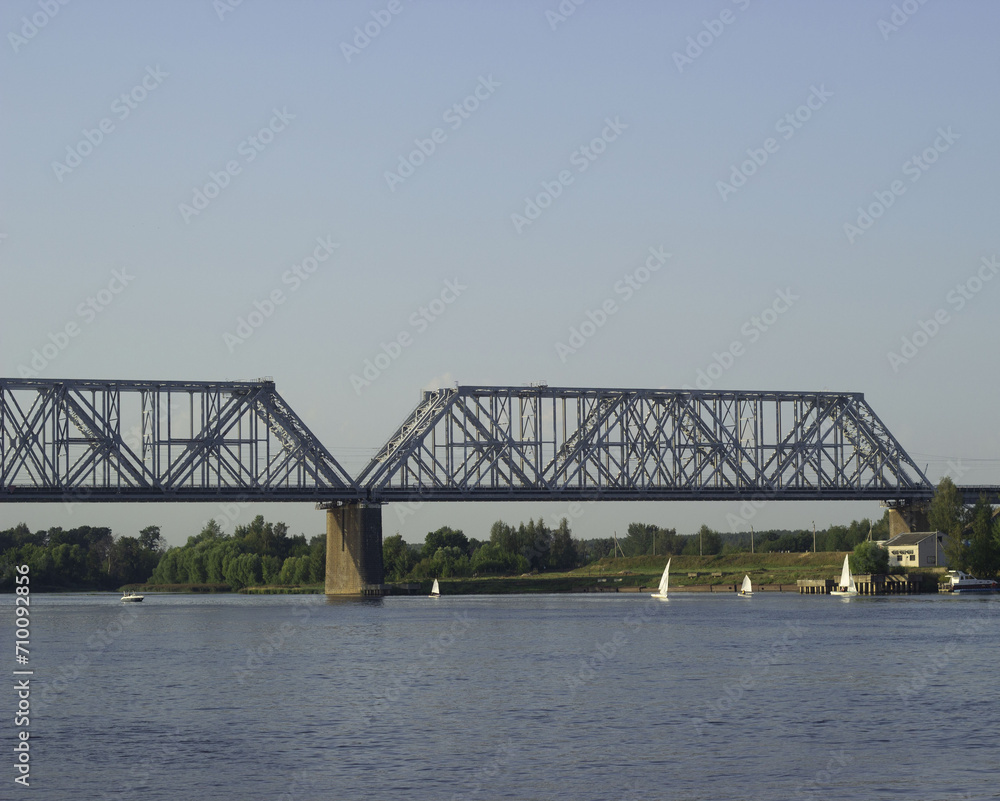 A huge beautiful railway bridge over the Volga River, a navigable span. Sailing boats sail along the river. A huge beautiful railway bridge over the Volga River, a navigable span. Sailing boats sail along the river.