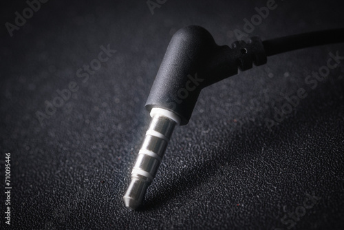 Audio Mini Jack plug on black background, metal glowing in the light, close-up macro photography photo