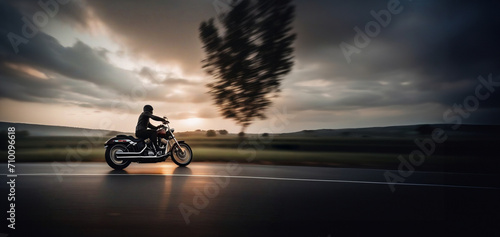 motorcyclist travels at sunset along the road on a chopper. © velimir