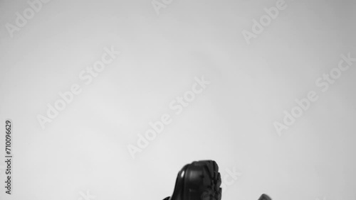 White and black shoes falling down against a white background. Fashionable thick sole sneakers falling down against a white background. Slow motion.  photo