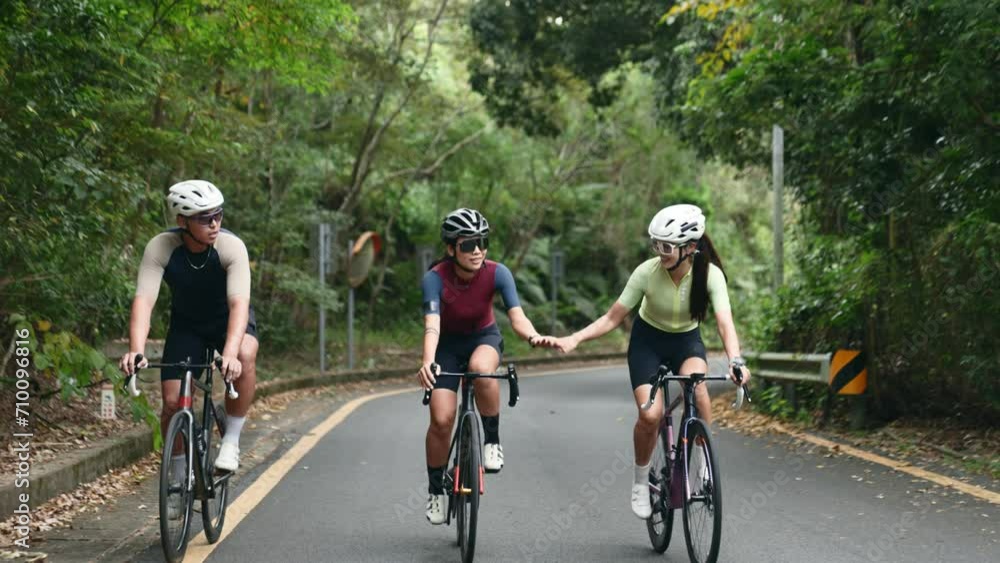 three happy and cheerful young asian cyclist friends riding bicycles on rural road three happy and cheerful young asian cyclist friends riding bicycles on rural road