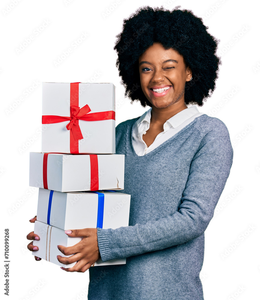 Young african american woman holding gifts winking looking at the camera with sexy expression, cheerful and happy face. Young african american woman holding gifts winking looking at the camera with sexy expression, cheerful and happy face.