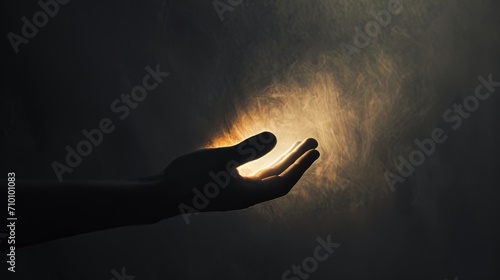 A conceptual photograph of a hand reaching out from the darkness towards a glowing light, symbolizing hope and uncertainty. The minimalistic composition and contrast of warm and cool tones. 
