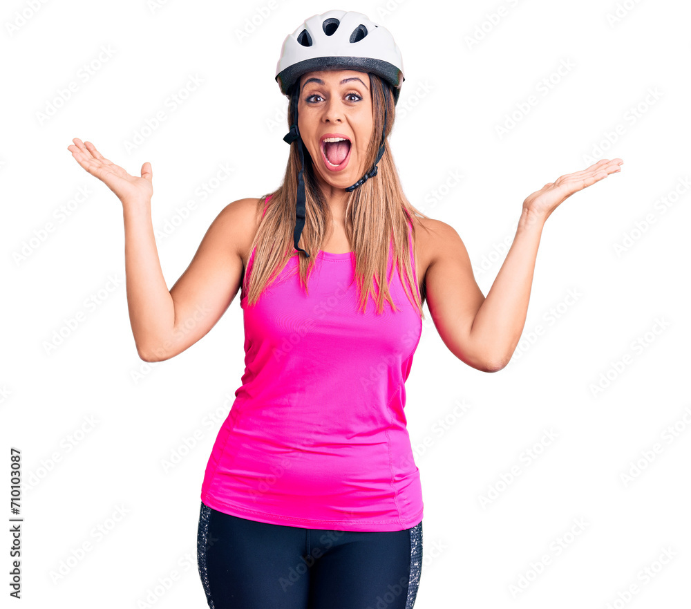 Young beautiful woman wearing bike helmet celebrating victory with happy smile and winner expression with raised hands Young beautiful woman wearing bike helmet celebrating victory with happy smile and winner expression with raised hands