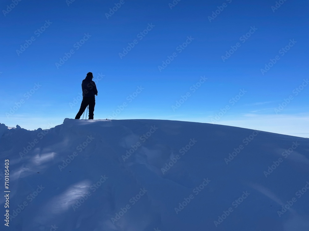 Silhouette of man standing on snow peak.