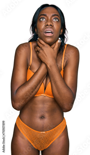 Young african american woman wearing lingerie shouting and suffocate because painful strangle. health problem. asphyxiate and suicide concept.