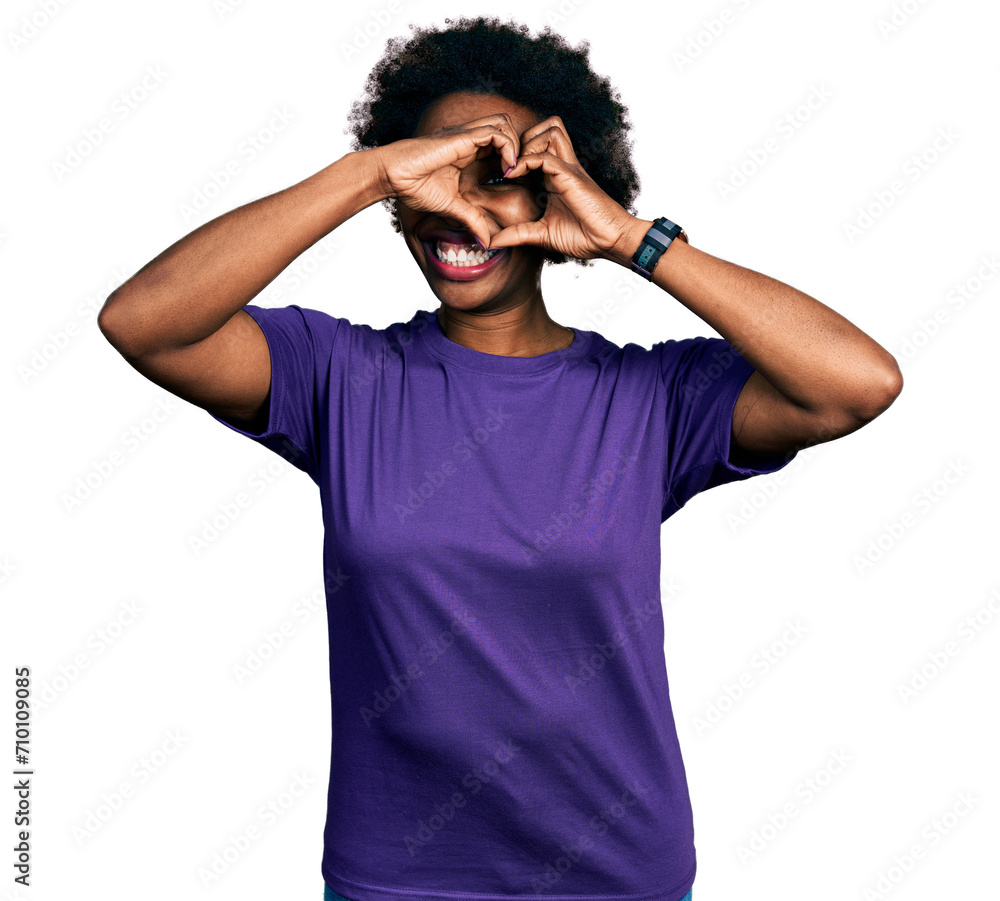 African american woman with afro hair wearing casual purple t shirt doing heart shape with hand and fingers smiling looking through sign African american woman with afro hair wearing casual purple t shirt doing heart shape with hand and fingers smiling looking through sign