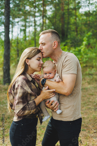 Happy young mother and father with a child on a walk in the park. The concept of a happy married couple with a child. Happy family couple with little newborn son in nature. © Дмитрий Ткачук
