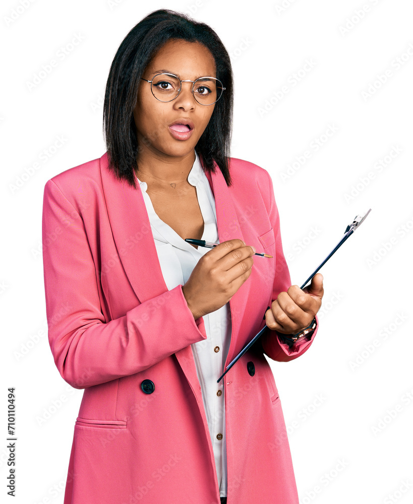 Beautiful hispanic woman holding clipboard in shock face, looking skeptical and sarcastic, surprised with open mouth Beautiful hispanic woman holding clipboard in shock face, looking skeptical and sarcastic, surprised with open mouth