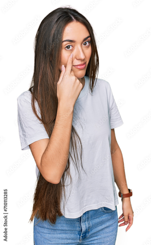 Young hispanic girl wearing casual white t shirt pointing to the eye watching you gesture, suspicious expression Young hispanic girl wearing casual white t shirt pointing to the eye watching you gesture, suspicious expression