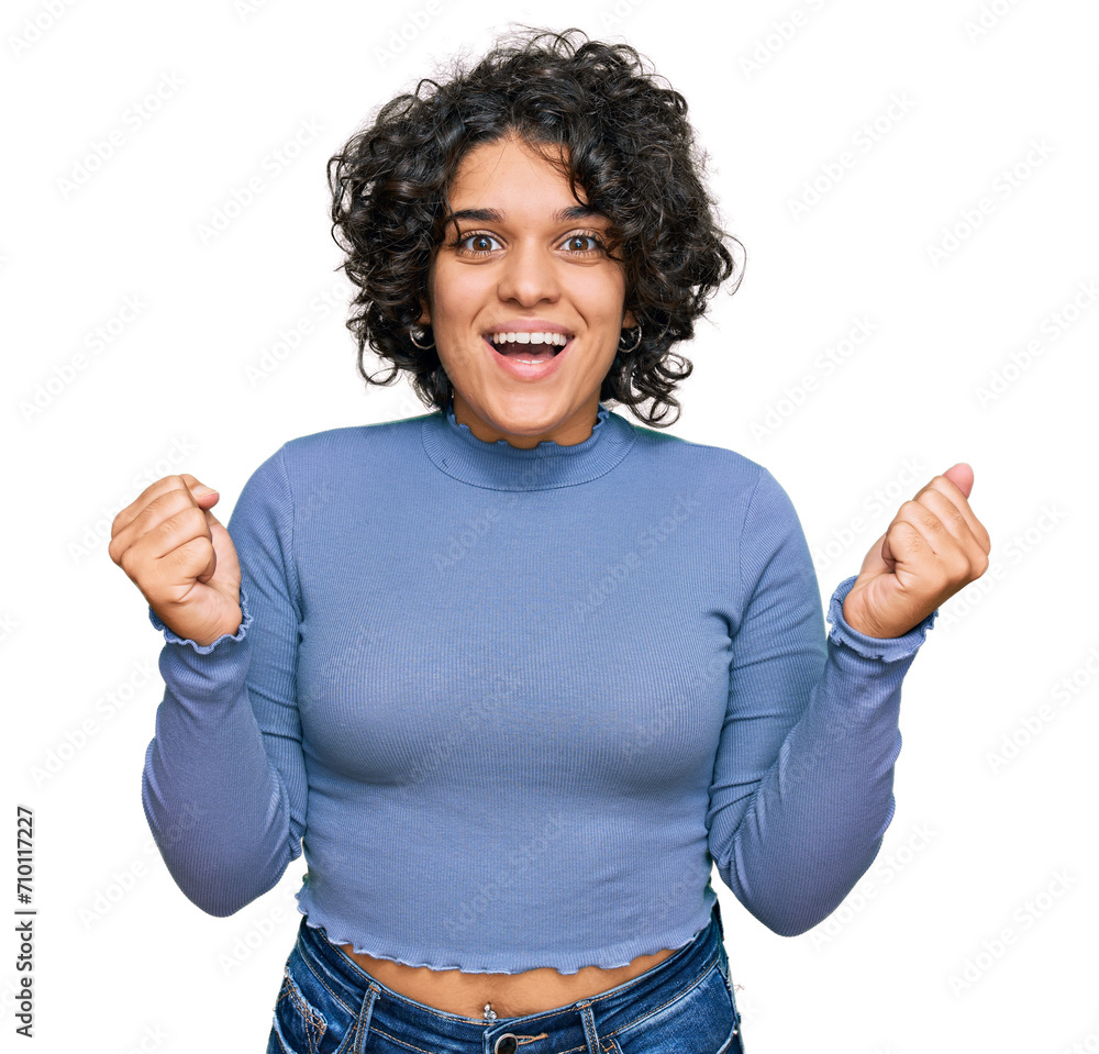 Young hispanic woman with curly hair wearing casual clothes celebrating surprised and amazed for success with arms raised and open eyes. winner concept. Young hispanic woman with curly hair wearing casual clothes celebrating surprised and amazed for success with arms raised and open eyes. winner concept.