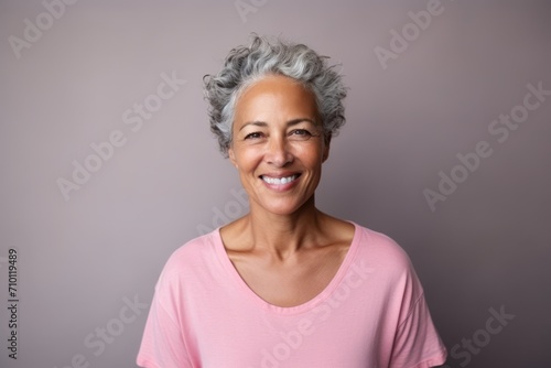 Portrait of a smiling senior woman with grey hair against a grey background