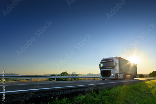 Large Transportation Truck on a highway road through the countryside at sunset