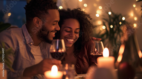 Happy Young Couple in Love Hugging  Laughing  Drinking Wine  Enjoying Talking  Having Fun Together Celebrating Valentine s Day Dining at Home. Having a Romantic Dinner Date with Candles  Sitting at a 