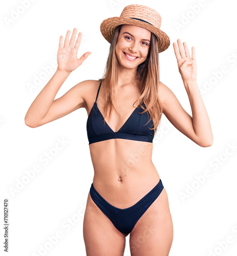 Young beautiful girl wearing bikini and hat showing and pointing up with fingers number nine while smiling confident and happy.