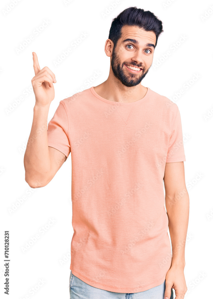 Young handsome man with beard wearing casual t-shirt with a big smile on face, pointing with hand and finger to the side looking at the camera. Young handsome man with beard wearing casual t-shirt with a big smile on face, pointing with hand and finger to the side looking at the camera.
