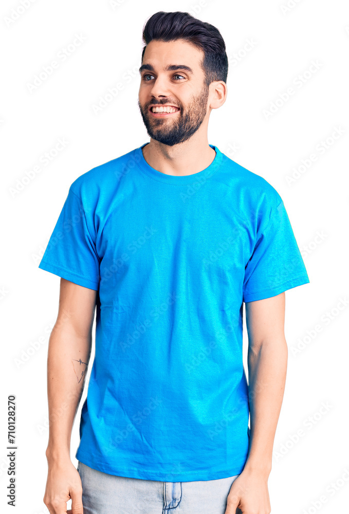Young handsome man with beard wearing casual t-shirt looking away to side with smile on face, natural expression. laughing confident. Young handsome man with beard wearing casual t-shirt looking away to side with smile on face, natural expression. laughing confident.