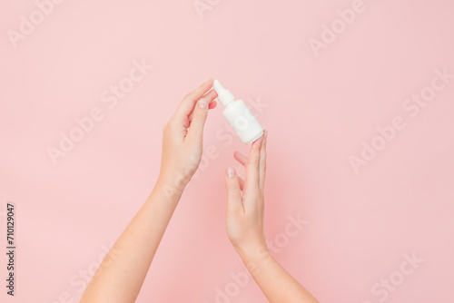 White bottle with serum lotion or essential oil (hyaluronic acid and collagen) in hands on pink background. Skin care cosmetics concept, beauty flyer © Anton Tolmachov