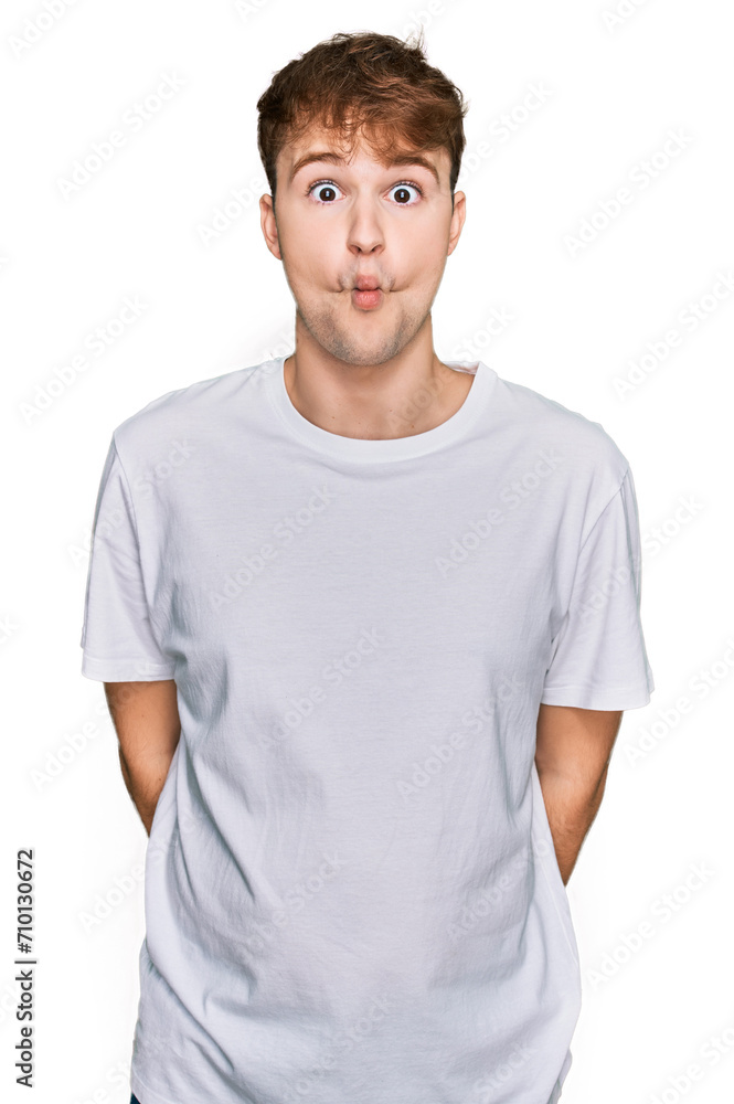 Young caucasian man wearing casual white t shirt making fish face with lips, crazy and comical gesture. funny expression. Young caucasian man wearing casual white t shirt making fish face with lips, crazy and comical gesture. funny expression.