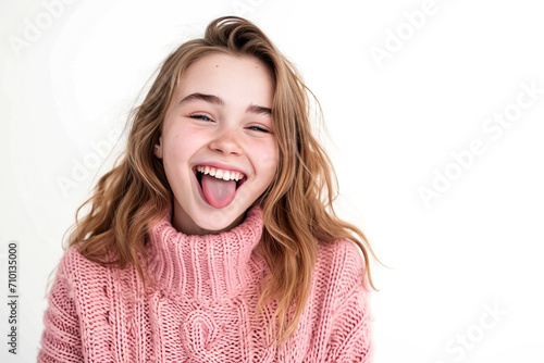 A beautiful Caucasian girl wearing a pink sweater on a white background with a happy and funny face, smiling and sticking out her tongue