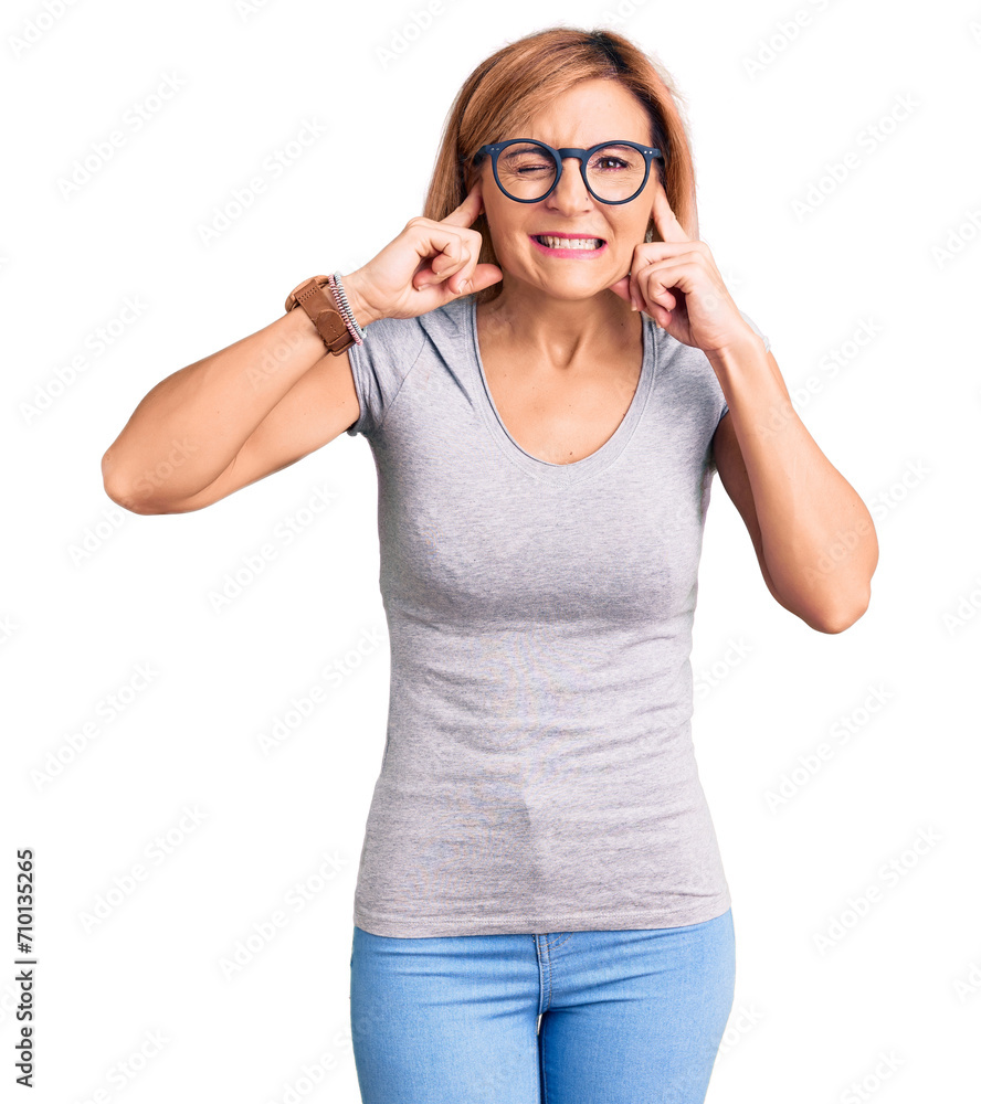 Young blonde woman wearing casual clothes covering ears with fingers with annoyed expression for the noise of loud music. deaf concept.