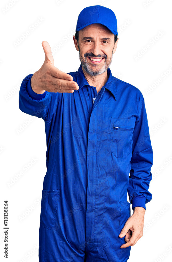 Middle age handsome man wearing mechanic uniform smiling friendly offering handshake as greeting and welcoming. successful business.