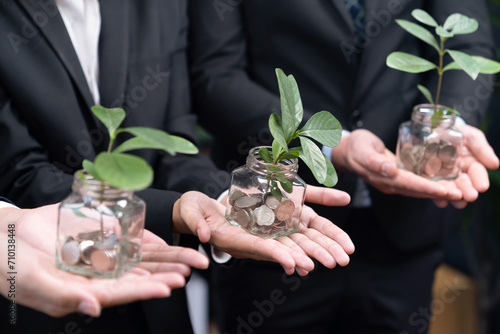 Business people holding money savings jar filled with coins and growing plant for sustainable financial planning for retirement or eco subsidy investment for environment protection. Quaint © Summit Art Creations