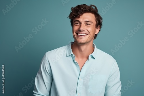 Portrait of a handsome young man smiling at the camera while standing against blue background