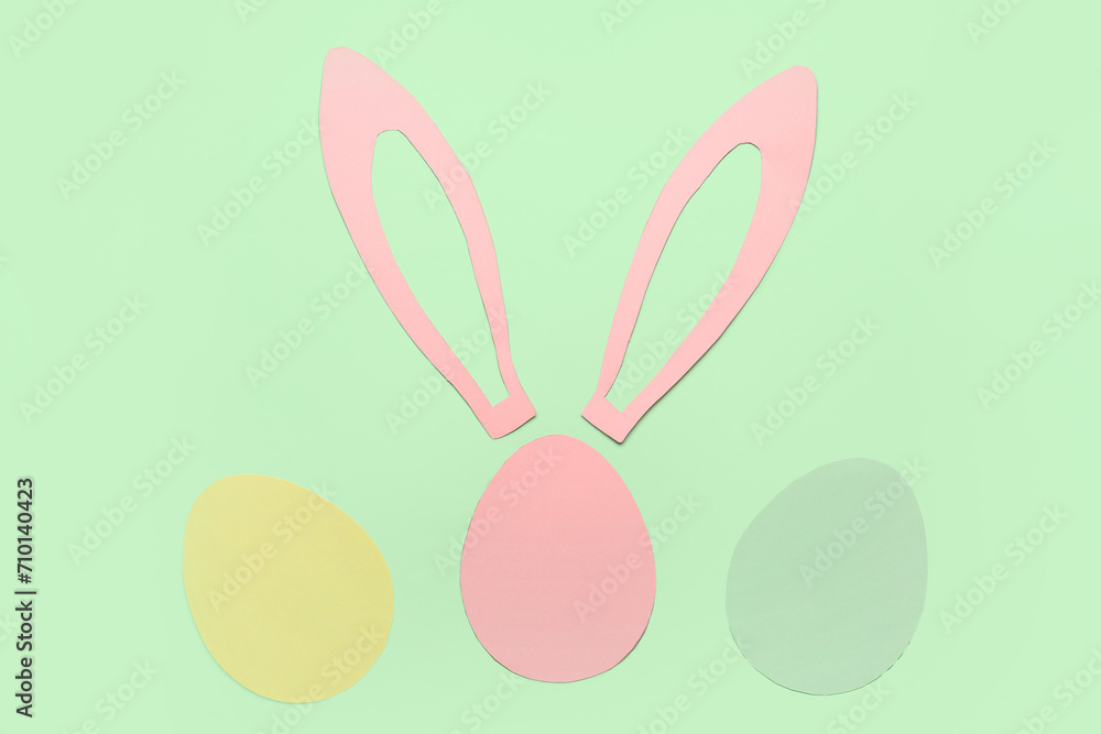 Fototapeta premium Paper bunny ears and Easter eggs on green background