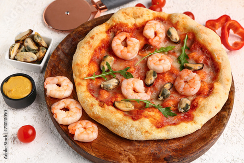 Plate with tasty seafood pizza on light background