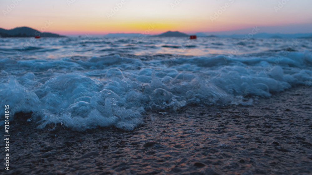 Closeup of wave on beach during sunrise or sunset with vivid colors in the sky