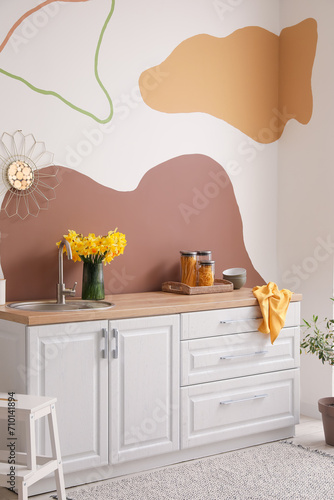 Interior of stylish kitchen decorated with blooming narcissus flowers