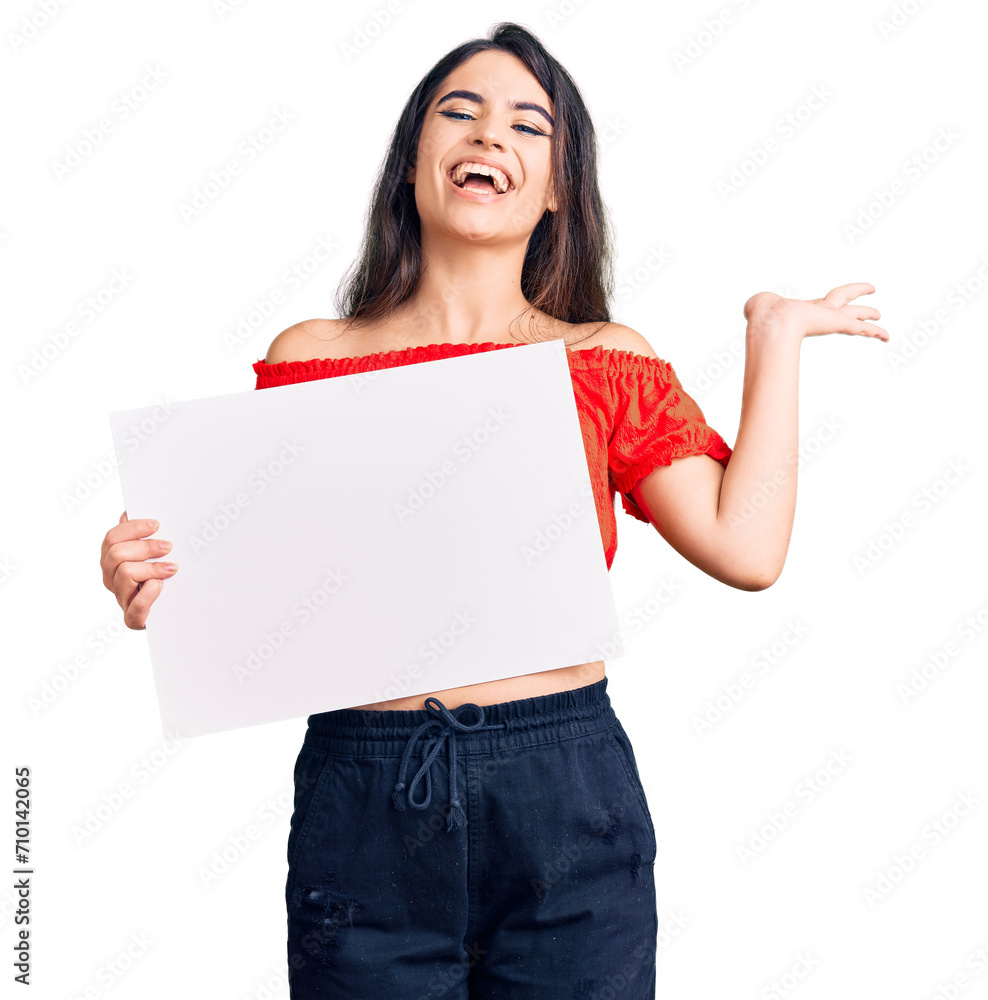 Brunette teenager girl holding blank empty banner celebrating victory with happy smile and winner expression with raised hands Brunette teenager girl holding blank empty banner celebrating victory with happy smile and winner expression with raised hands
