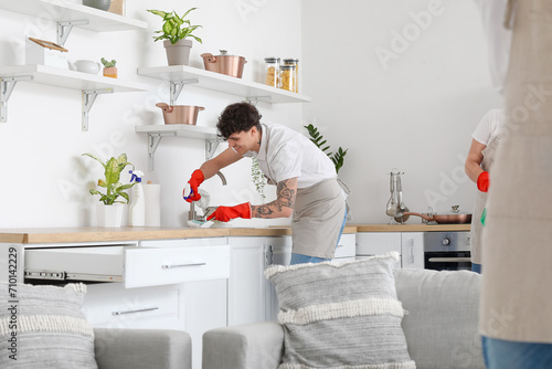 Male janitor cleaning sink in kitchen