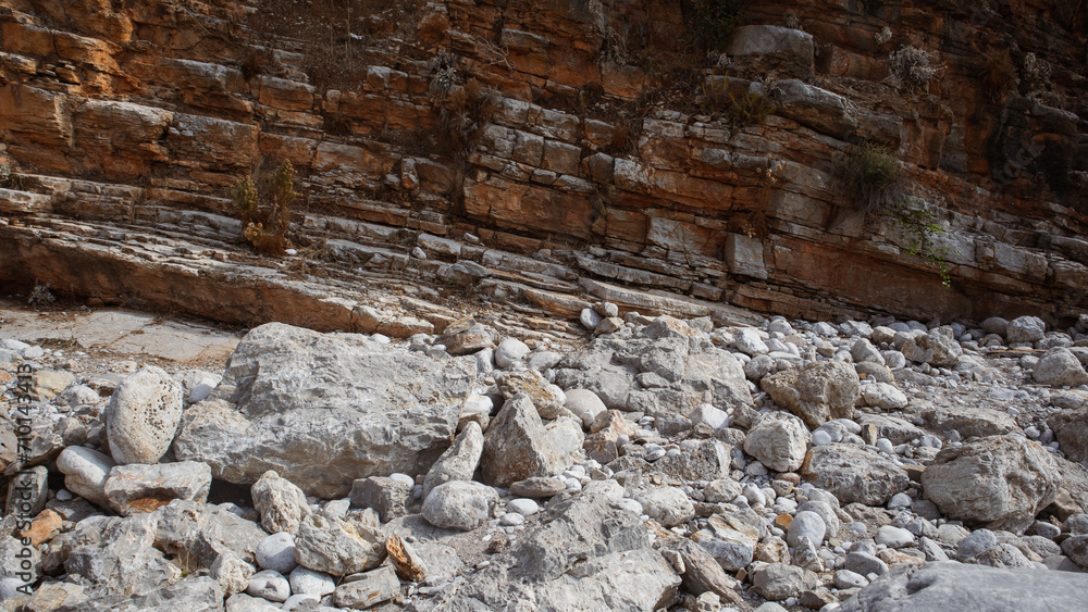 Eroded rocky cliff texture, photo of sandy rocks and dark brown color layered stone wall