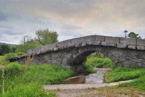 Ancient bridge built in stone over a small river, sky with sunset