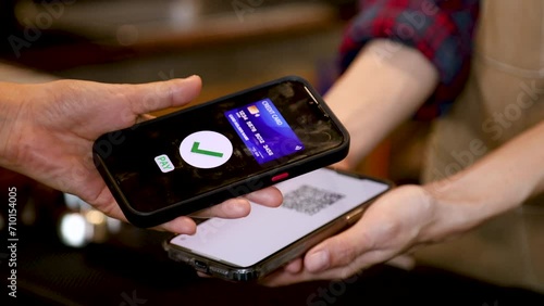 Closeup customer hand hold mobilephone making cashless payment in retails small business cafe coffee restaurant shop, cashier using qr code billing credit card, contactless online wireless application photo