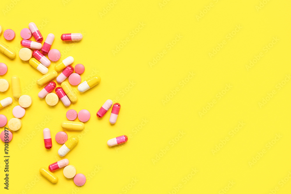 Many different pills on yellow background