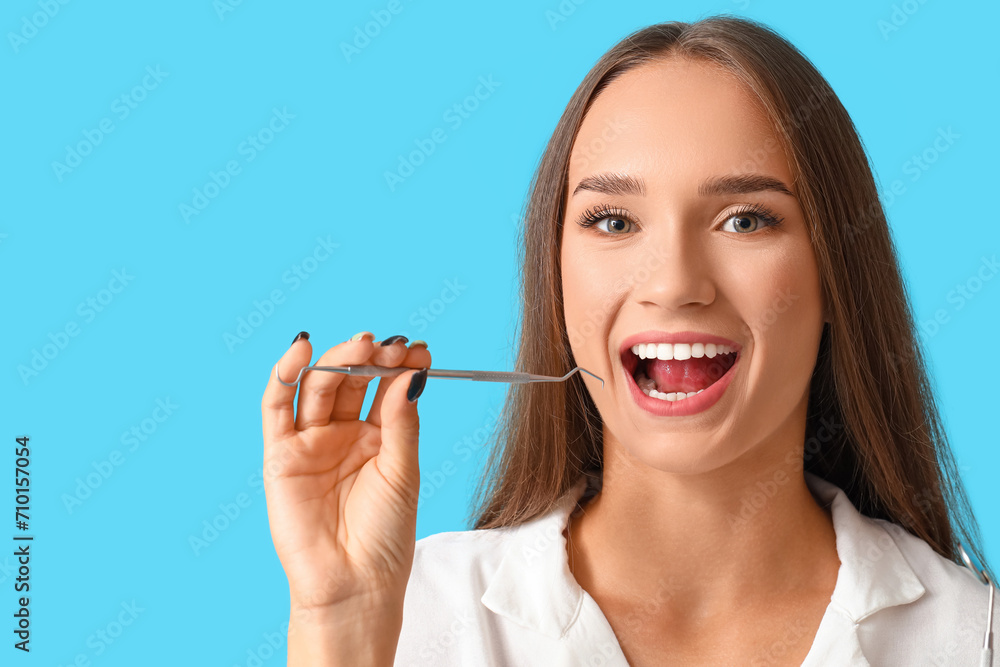 Smiling young woman with dental tool on blue background Smiling young woman with dental tool on blue background
