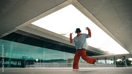 Motion shot of professional hipster listening music while perform freestyle dance. Street dancer moving and waving and enjoy practice break dance. Modern lifestyle. Outdoor sport 2024. Sprightly.