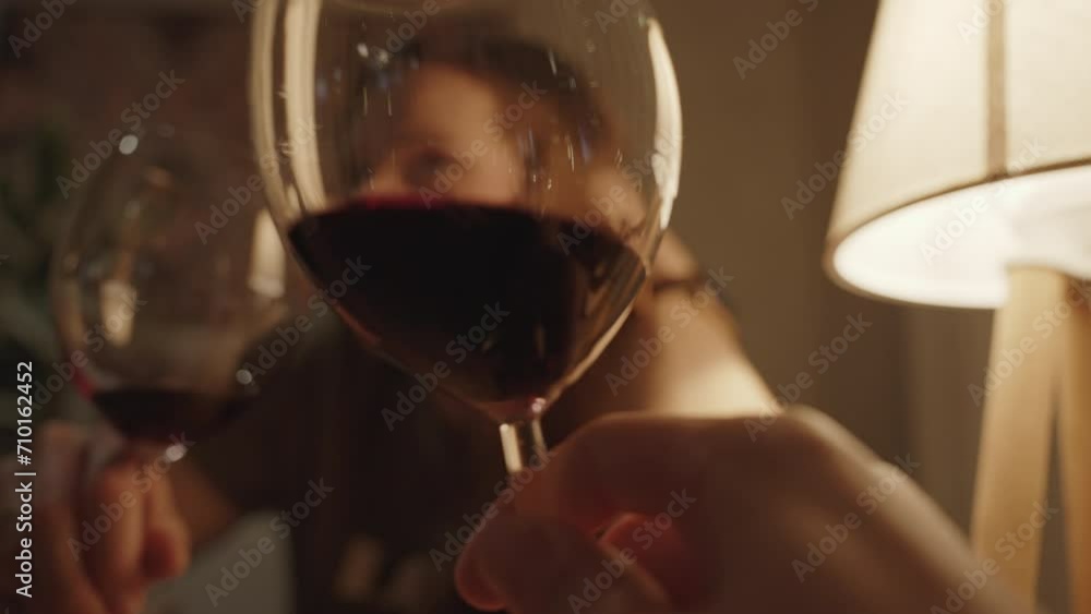 A Man Holds and Swirls a Glass of Red Wine, Watching as a Woman Tells Something. A Date in Warm Romantic Light. A Man Holds and Swirls a Glass of Red Wine, Watching as a Woman Tells Something. A Date in Warm Romantic Light.