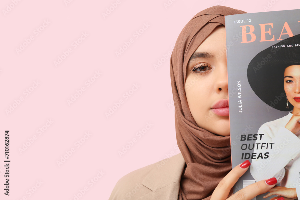 Beautiful young Muslim woman in hijab with magazine on pink background ...