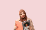 Beautiful young Muslim woman in hijab with magazine on pink background