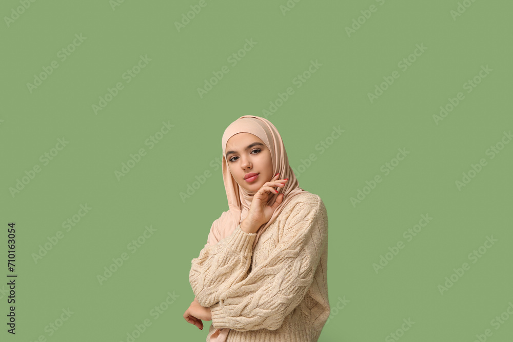 Fototapeta premium Pretty young Muslim woman in hijab on green background