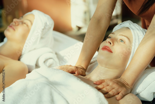 A portrait of two beautiful woman having back massage by professional masseur and falling in deep relaxation surrounded by traditional spa environment. Calming and relaxing concept. Tranquility.