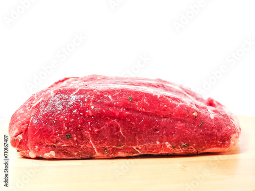 Uncooked strip loin joint on old wooden board and on white background. Raw high quality and price piece of beef meat.