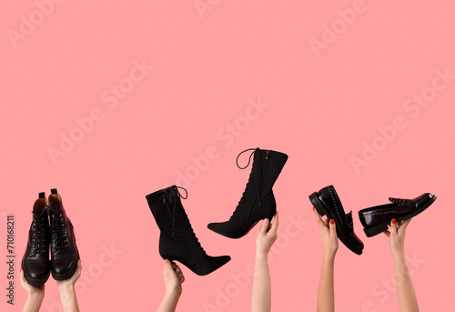 Female hands holding different shoes on pink background photo